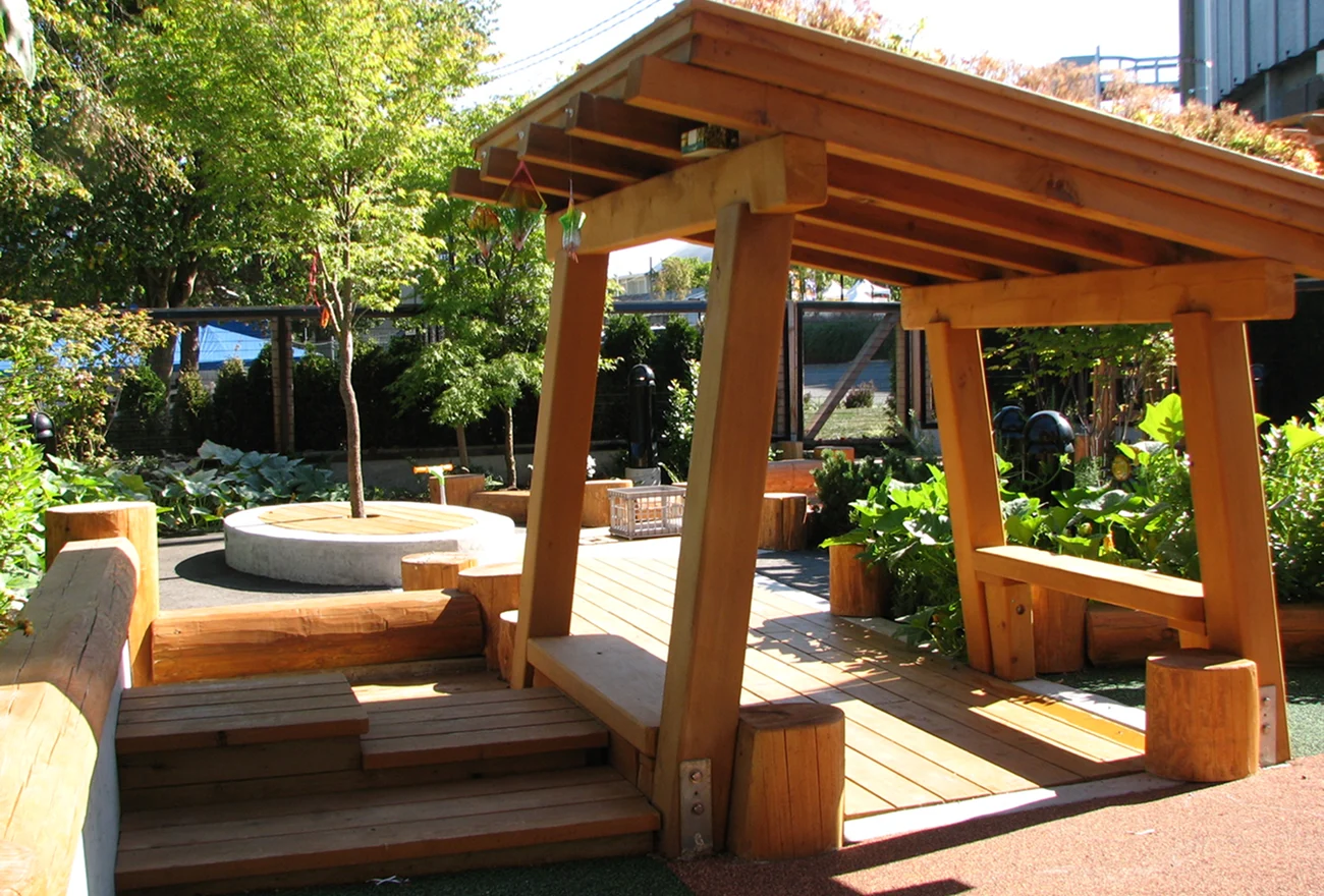 Timber pergola over wooden decking and benches in a planted courtyard garden