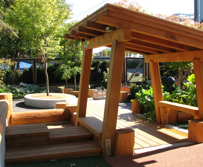 Timber pergola over wooden decking and benches in a planted courtyard garden