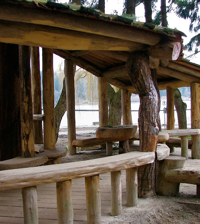 Log shelter with a natural tree-trunk post and log bench seating